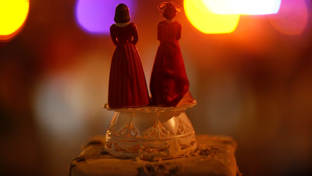Two bride figurines on top of a cake.