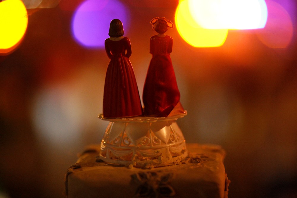 Two bride figurines on top of a cake.