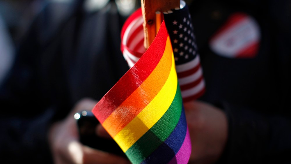 Marriage equality supporter Gus Thompson holds gay pride and American flags at a demonstration t the 9th District Court of Appeals in San Francisco