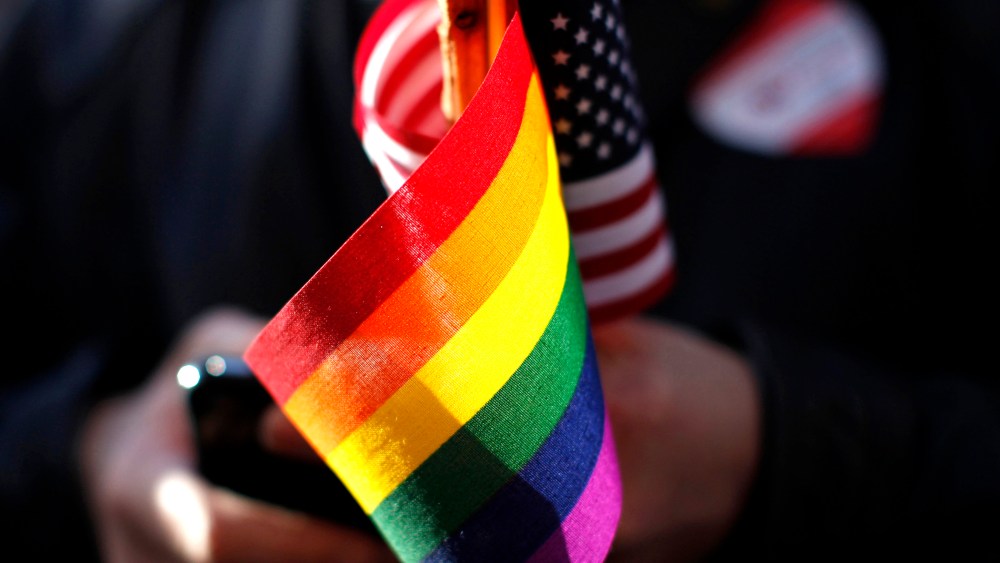 A marriage equality supporter holds gay pride and American flags at a demonstration.
