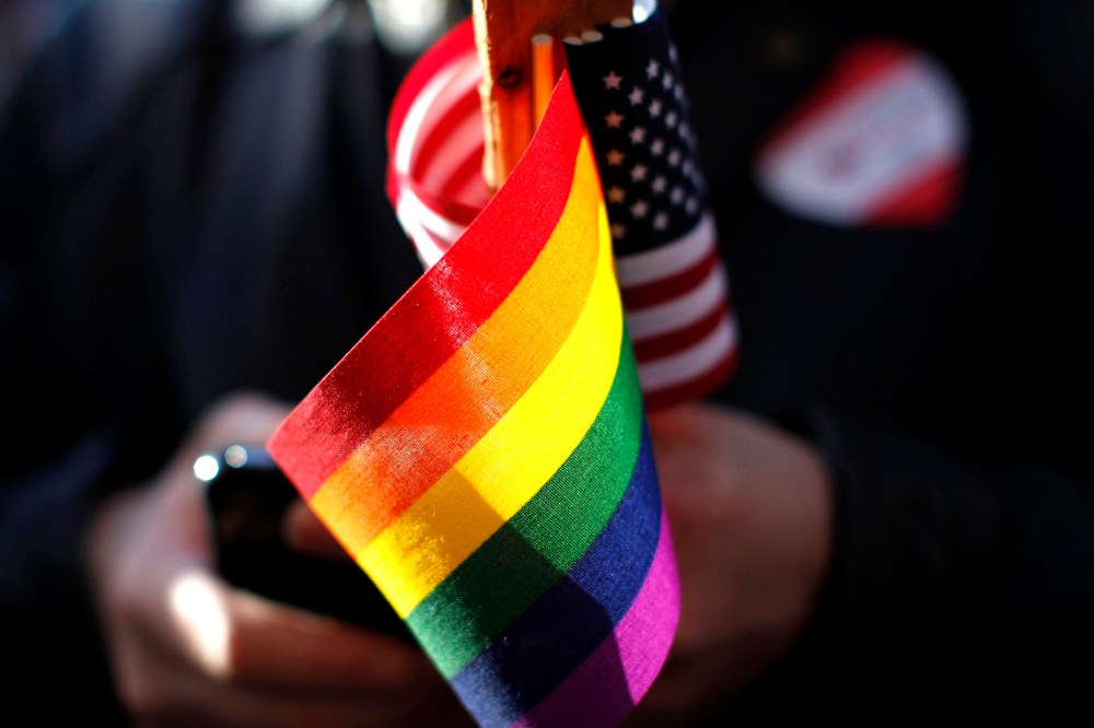 A marriage equality supporter holds gay pride and American flags at a demonstration.