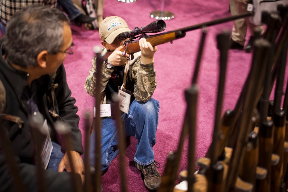 A child checks out a hunting rifle at the Safari Club International Convention in Reno, Nevada, January 29, 2011.