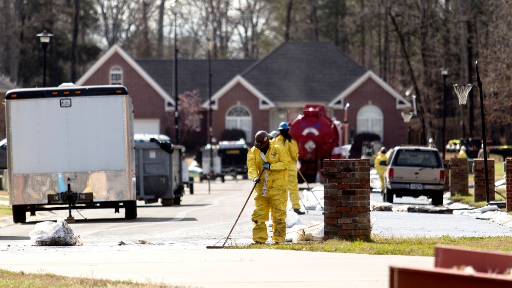 Emergency crews work to clean up an oil spill in front of evacuated homes on Starlite Road in Mayflower