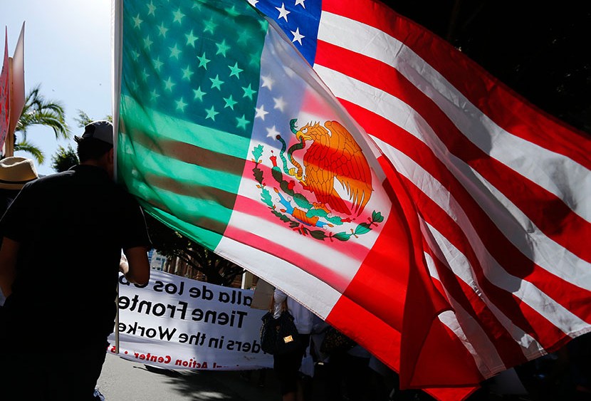 A young man carries national flags of the U.S. and Mexico through the streets during a May Day march, May 1, 2013, in San Diego, Calif.