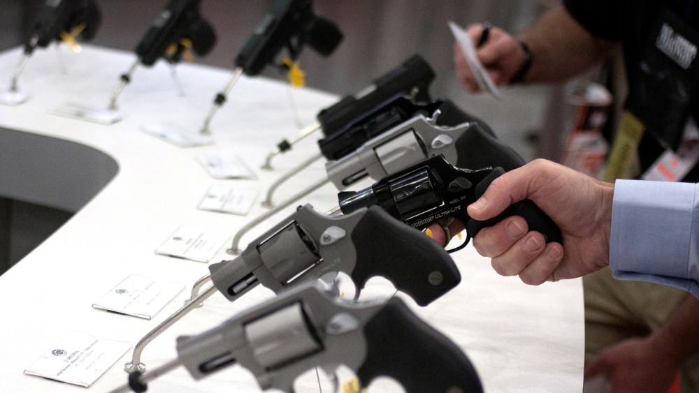 Man holds a gun in the exhibit hall of the George R. Brown Convention Center, the site for the NRA's annual meeting in Houston, Texas