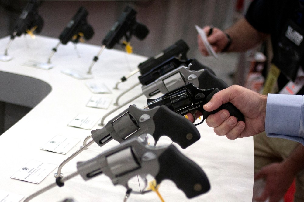 Man holds a gun in the exhibit hall of the George R. Brown Convention Center, the site for the NRA's annual meeting in Houston, Texas