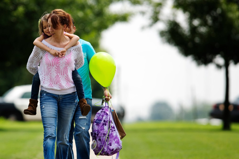 Jayme Sheppard carries her daughter as she departs for school in Oklahoma City, Oklahoma, May 23, 2013.