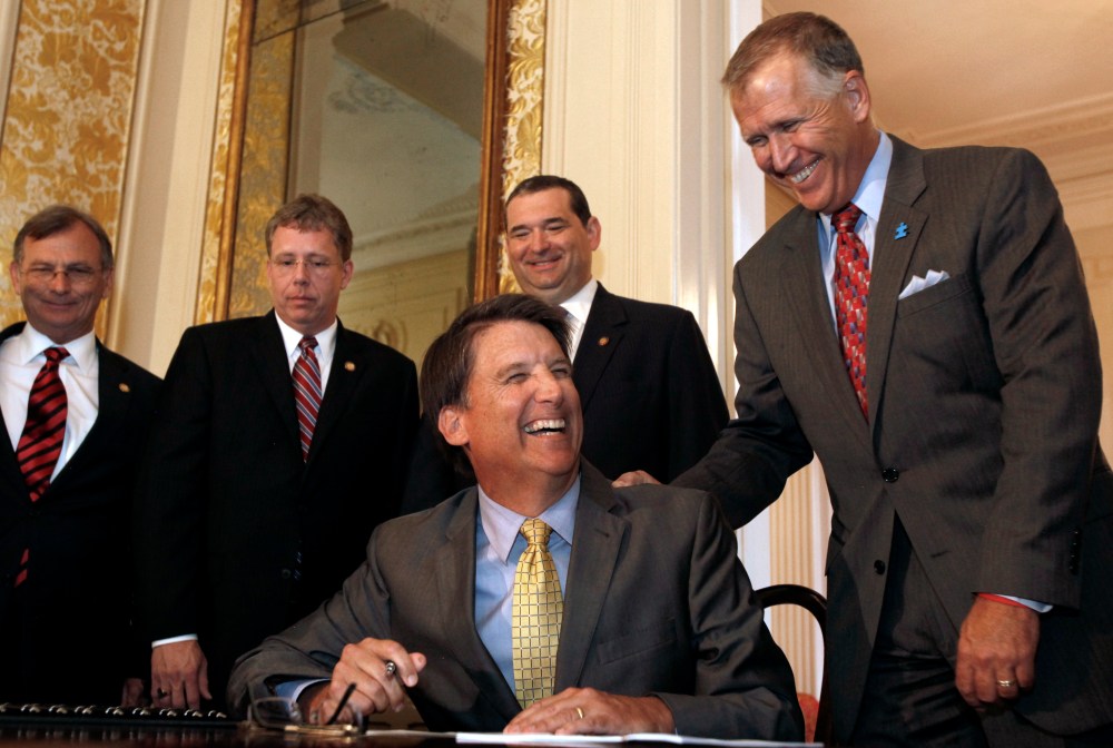 Gov. Pat McCrory, flanked by members of the N.C. General Assembly like Speaker of the House Thom Tillis, right, jokes before he signs the HB 998 for Tax Reform in the ballroom at the Executive Mansion in Raleigh, N.C. on Tuesday, July 23, 2013. (AP...