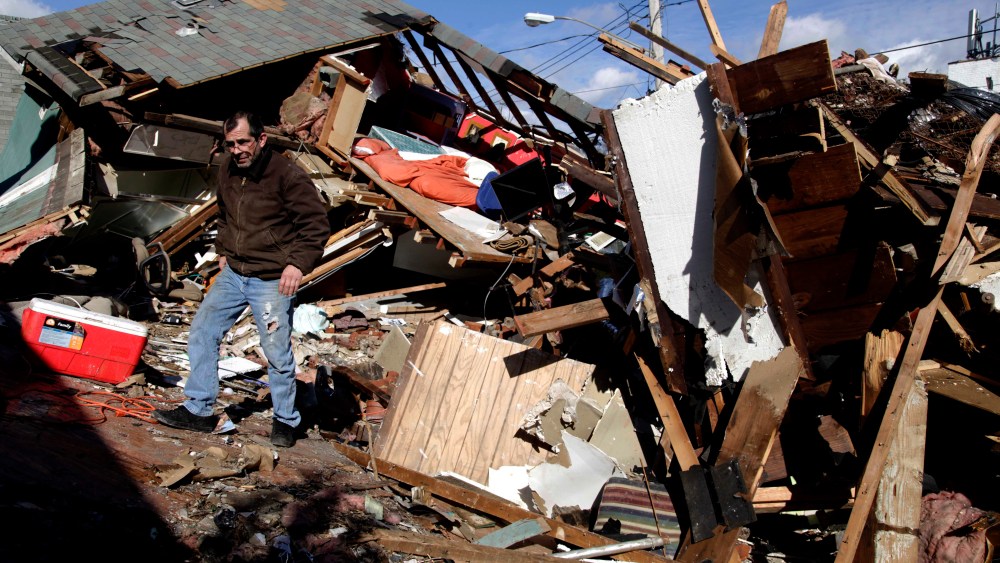 James Traina climbs over the remains of his parent's house which was destroyed by Superstorm Sandy in Staten Island, N.Y. Friday, Nov. 2, 2012. (AP Photo/Seth Wenig)