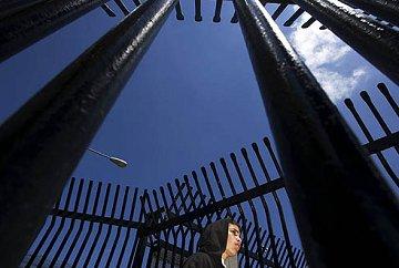 A young man stands in the gates at the U.S.-Mexico border awaiting his deportation at the port of entry in Tijuana.
