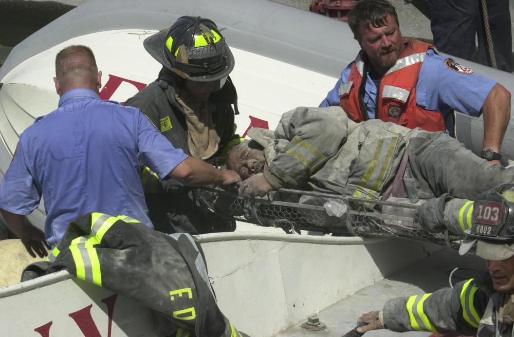 Firefighters carry an injured fireman from the World Trade Center area in New York after the buildings collapsed Tuesday, Sept. 11, 2001, after two planes crashed into the structure.