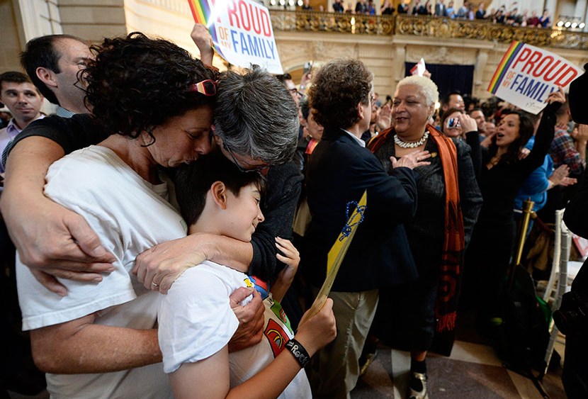Sue Rochman (L) and her partner Robin Romdalvik of San Francisco, (third L) kiss their eight-year-old son, Maddox (second L), as they listen to the Supreme Court rulings on California's Prop 8 ban on same-sex marriages as well as on the Defense of...