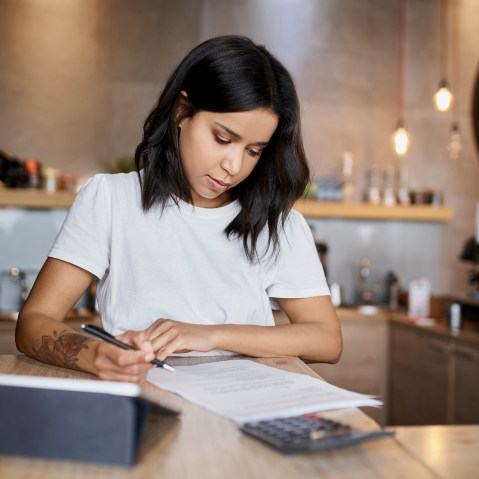 Female cafe owner signing papers calculating business expenses
