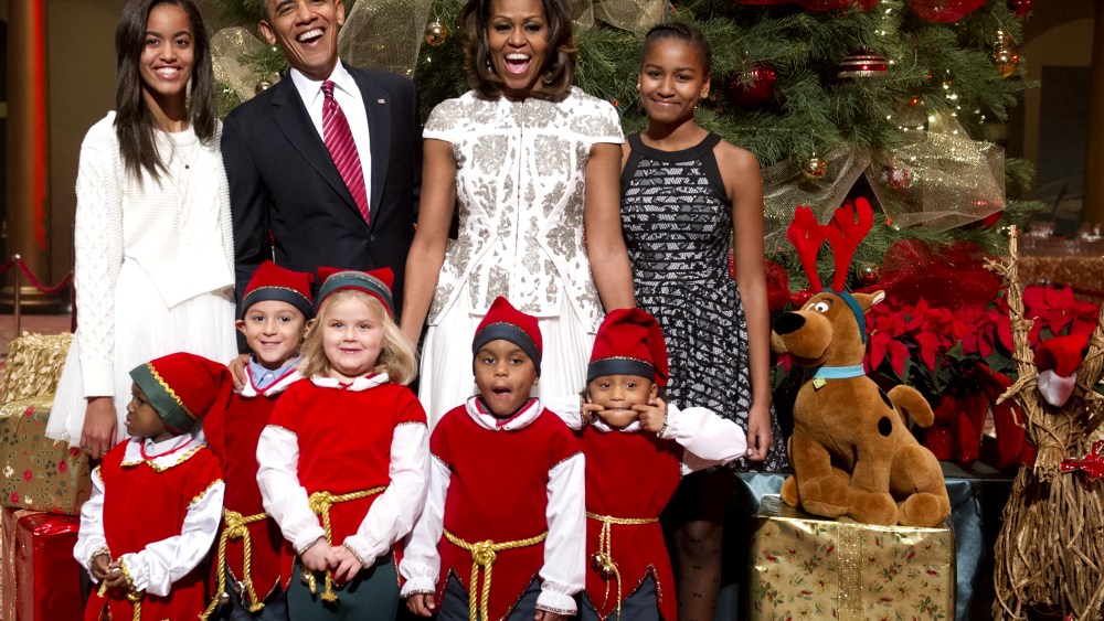 US President Barack Obama, First Lady Michelle Obama and their daughters, Sasha (R) and Malia (L), pose for photographs alongside children dressed as elves in Washington on Dec. 15, 2013.