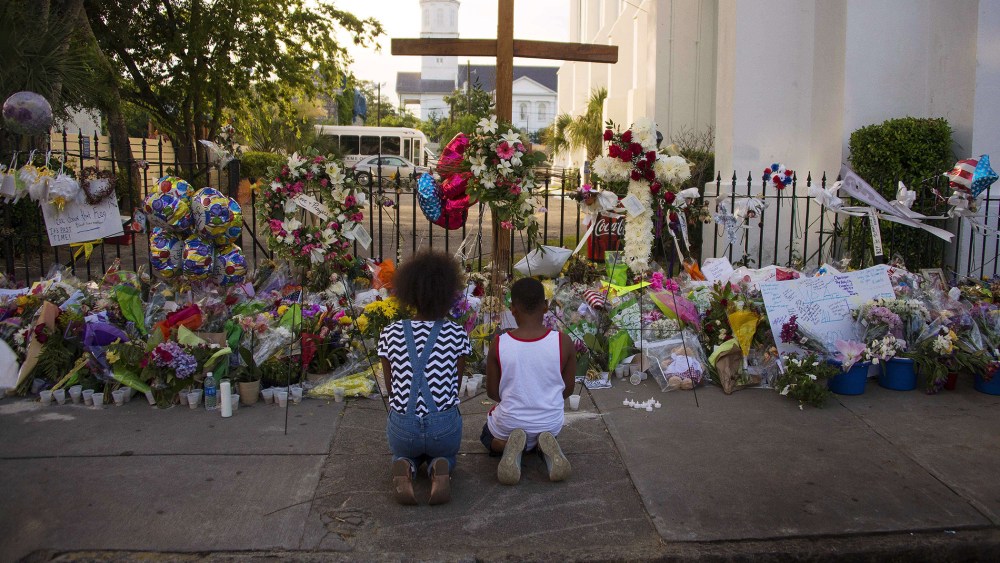Two children pray near thousands of flowers and cards left in condolence outside Emanuel AME Church in Charleston, S.C., on June 23, 2015. (Photo by Jim Watson/AFP/Getty)