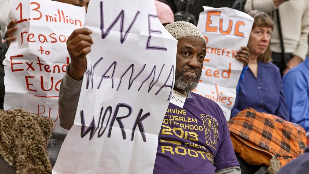 Audience members hold signs appealing for jobs as they attend a Democratic news conference about extending unemployment insurance benefits which expired Dec. 28, Wednesday, Jan. 8, 2014, on Capitol Hill in Washington.