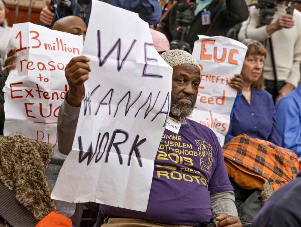 Audience members hold signs appealing for jobs as they attend a Democratic news conference about extending unemployment insurance benefits which expired Dec. 28, Wednesday, Jan. 8, 2014, on Capitol Hill in Washington.