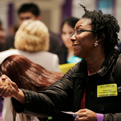 Susan Paul, who has recently completed a Masters program in occupational therapy, shakes hands with a recruiter at a healthcare job fair, Thursday, March 14, 2013, in New York.   (Photo by Mark Lennihan/AP)