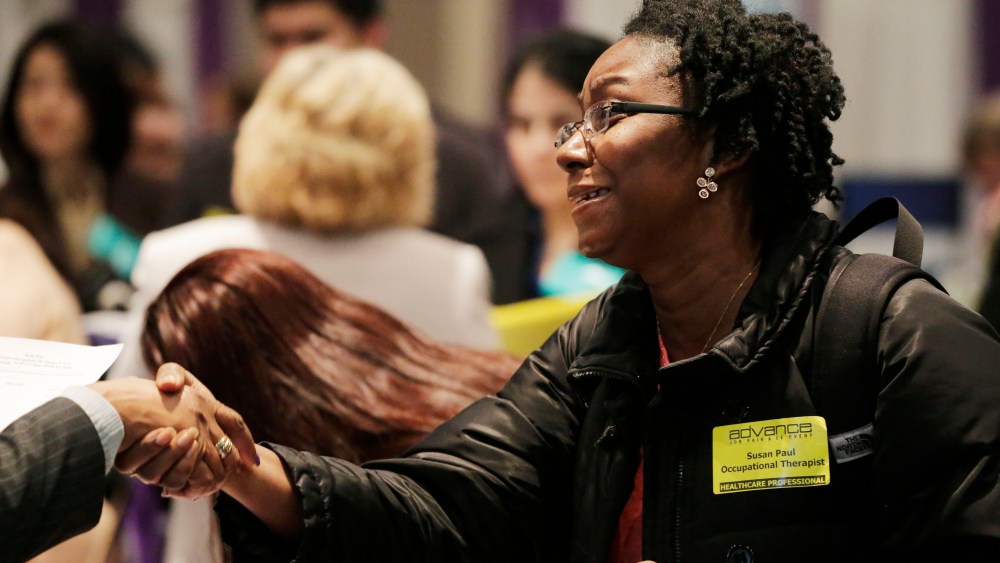 Susan Paul, who has recently completed a Masters program in occupational therapy, shakes hands with a recruiter at a healthcare job fair, Thursday, March 14, 2013, in New York.   (Photo by Mark Lennihan/AP)