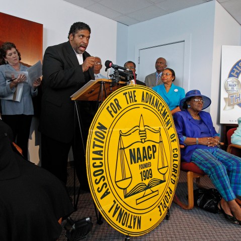 The Rev. William Barber, head of the North Carolina NAACP, at podium,  announces that the group is filing a lawsuit against the recently passed Voter ID bill during a press conference held in Durham, NC on Tuesday August 13, 2013.  Seated are...