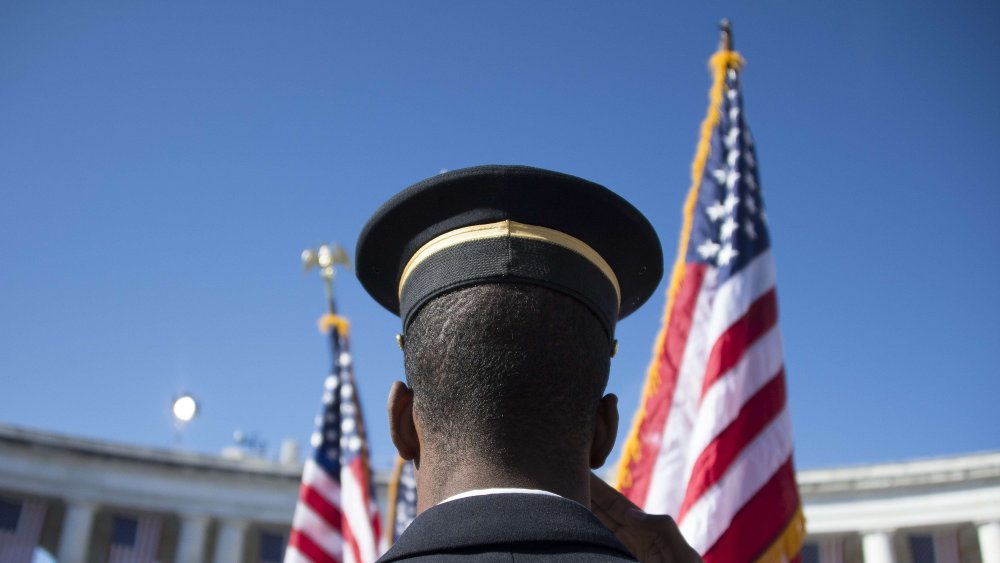 A member of the US Army Honor Guard salutes as the colors are presented during a Veteran's Day ceremony at Arlington National Cemetery in Arlington, Va. on Nov. 11, 2013.