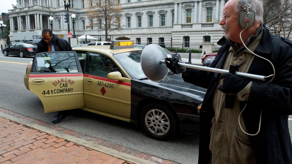 An activist dressed as spy using a listening device demonstrates at the Office of the U.S. Trade Representative in Washington, D.C., on December 16, 2013.