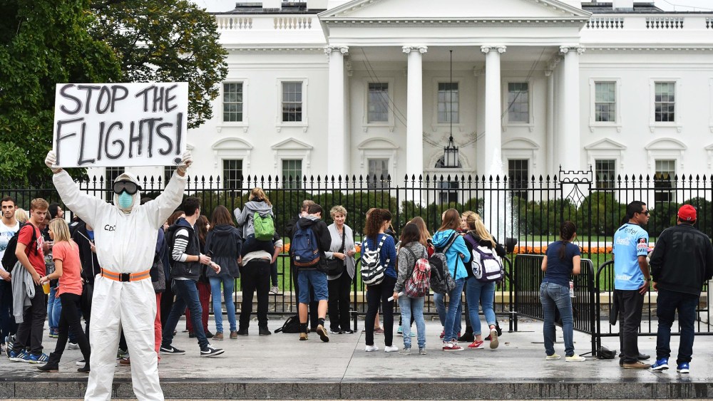 Jeff Hulbert from Annapolis, Md., dressed in a protective suit and mask, holds a poster demanding for a halt of all flights from West Africa as he protests outside the White House in Washington, D.C. on Oct. 16, 2014.