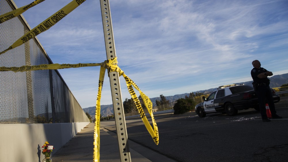 A San Bernardino police officer stands on the perimeter as crime scene tape and flowers rest near the Inland Regional Center on Dec. 3, 2015 in San Bernardino, Calif. (Photo by Patrick T. Fallon/AFP/Getty)