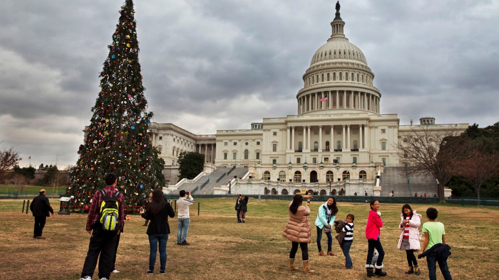 Under rolling clouds, tourists remove their jackets as they visit the U.S. Capitol Christmas tree in Washington, Sunday, Dec. 22, 2013.