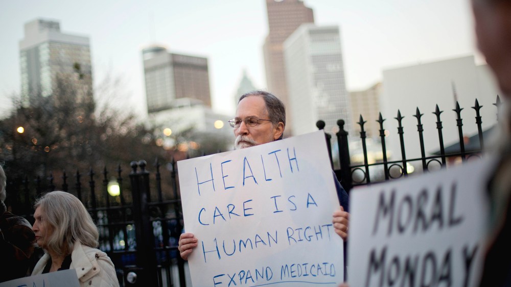 Bert Skellie, of Decatur, Ga., protests for Medicaid expansion outside the Wild Hog Supper, Sunday, Jan. 12, 2014, in Atlanta.
