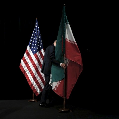 A staff removes the Iranian flag from the stage after a group picture with foreign ministers and representatives during the Iran nuclear talks at the Vienna International Center in Vienna