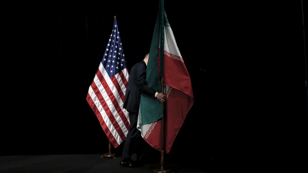 A staff removes the Iranian flag from the stage after a group picture with foreign ministers and representatives during the Iran nuclear talks at the Vienna International Center in Vienna