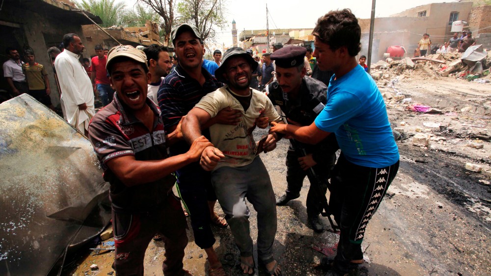 Men react at the site of a car bomb attack at a market in the town of Iskandariya