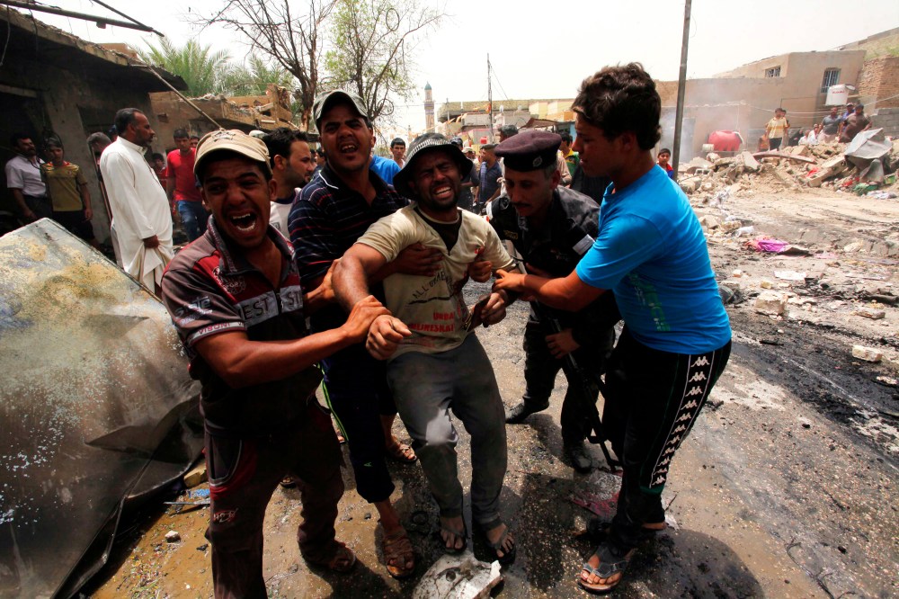 Men react at the site of a car bomb attack at a market in the town of Iskandariya