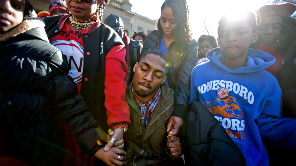 Leon Ford, center, joins hands with supporters during a rally in memory of Kendrick Johnson, the Georgia teenager found dead inside a rolled-up wrestling mat in his school, Dec. 11, 2013, in Atlanta.