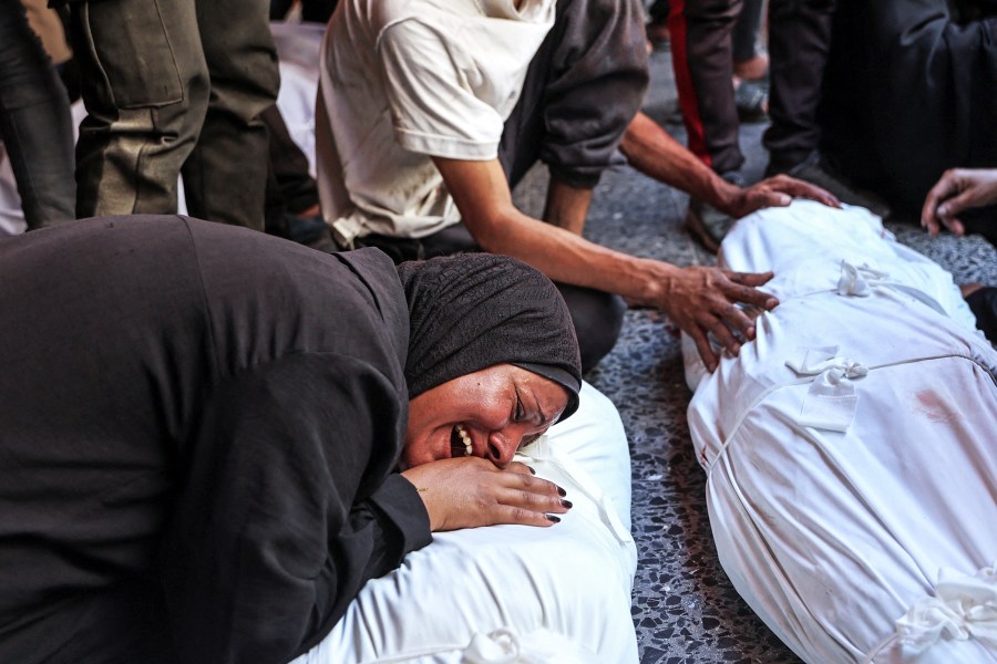 A woman cries over a body covered in white tarp