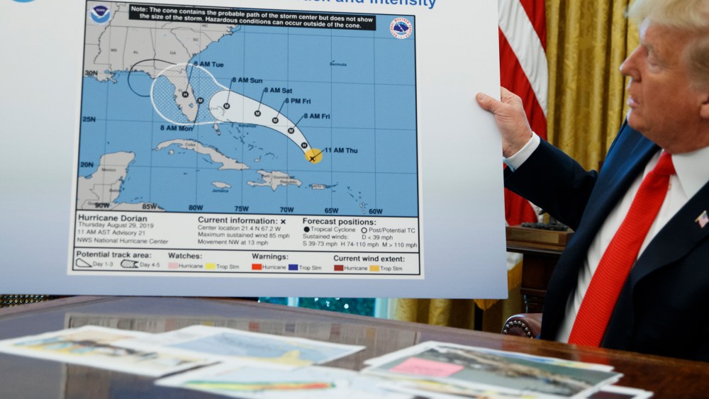 Donald Trump holds a NOAA map.
