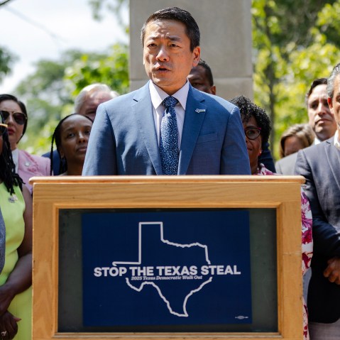 Gene Wu speaks at a podium outside surrounded by other people