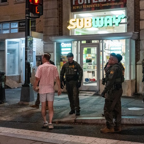 Sean Dunn holds a sandwich as he interacts with Border Patrol and FBI agents outside of a Subway location holding a sandwich