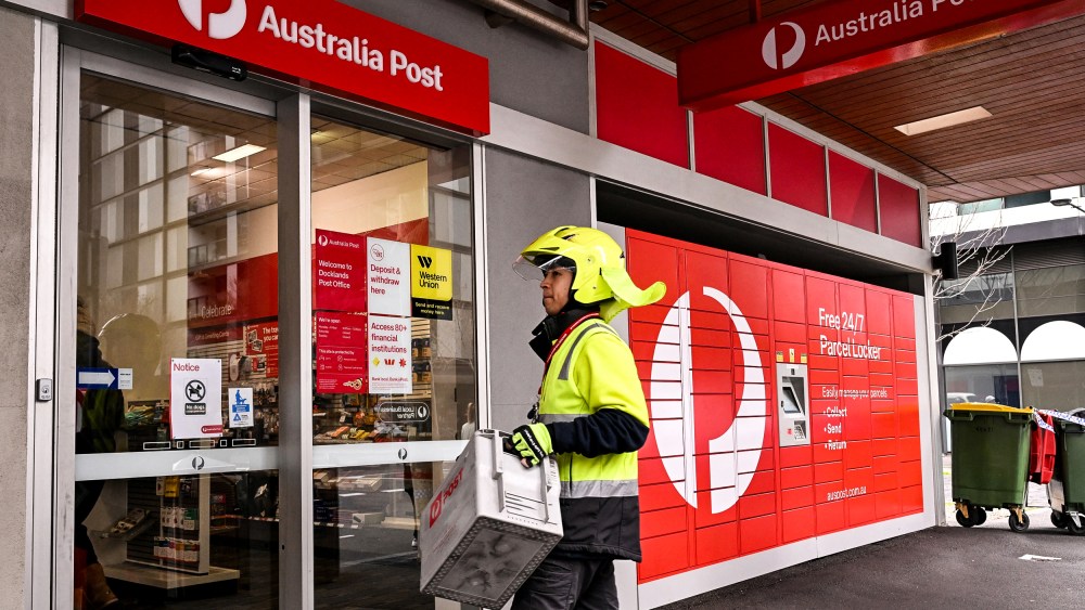 Image: A postman enters an Australia Post store