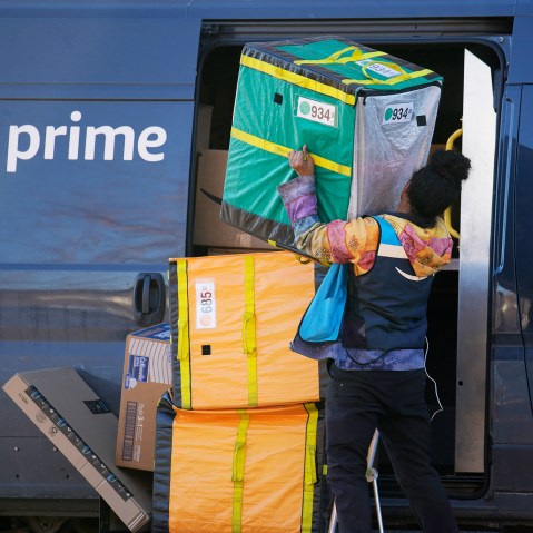 An Amazon Prime delivery person lifts packages while making a stop