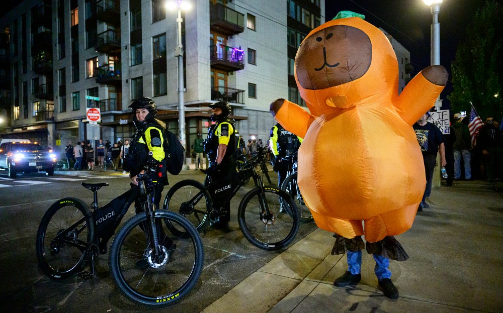 Portland Police officers stand watch as a protestors demonstrates near an Immigration and Customs Enforcement (ICE) facility.