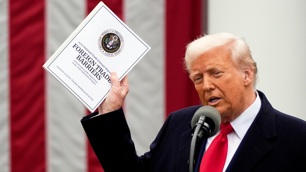 US President Donald Trump speaks during a tariff announcement, holding a "Foreign Trade Barriers" booklet.