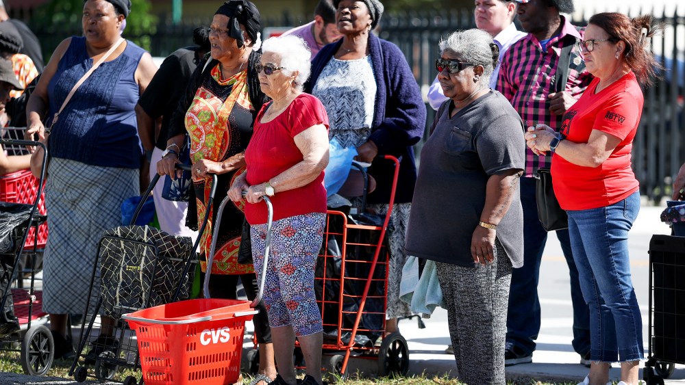 People wait in line to receive groceries from a food bank in Miami, F.L.
