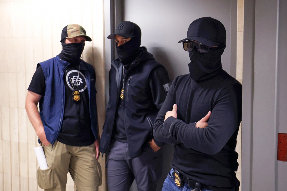 Federal agents wearing face coverings wait outside a courtroom.