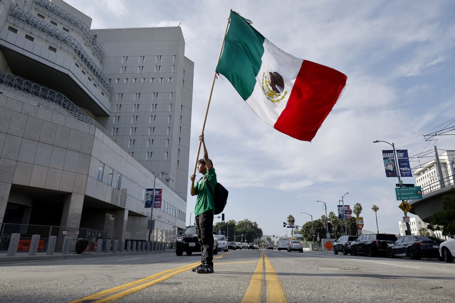 A man waves a Mexican flag behind the Edward R. Roybal Federal Building in Los Angeles.