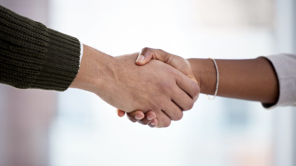 Closeup shot of two businesspeople shaking hands in an office.