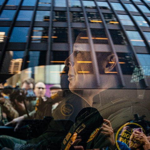 U.S. Border Patrol commander Gregory Bovino sits in the driver's seat surrounded by media and protesters.