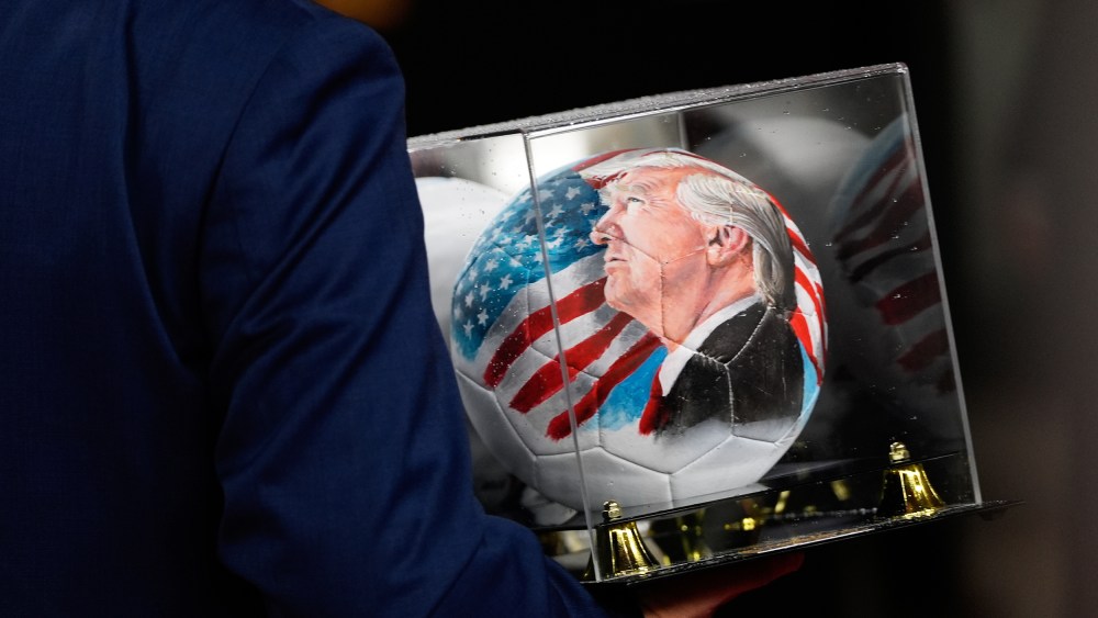 A person carries a soccer ball with a painting of President Donald Trump in D.C.