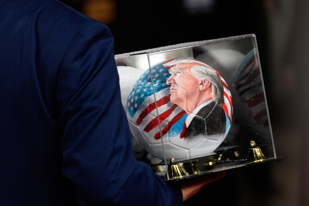 A person carries a soccer ball with a painting of President Donald Trump in D.C.